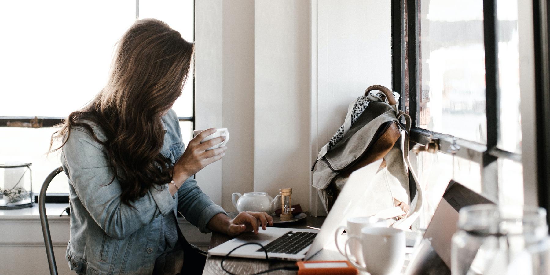 woman sitting drinking coffee and writing